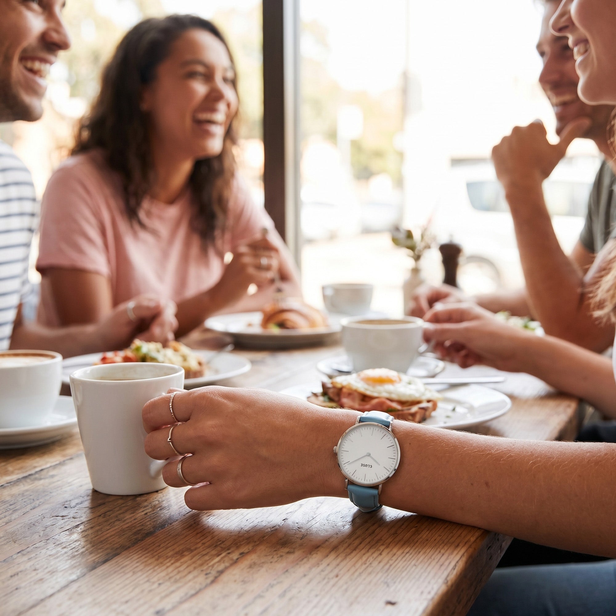 Woman wearing Cluse La Boheme silver white/pastel baby blue watch at a social gathering.