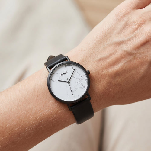Woman wearing Cluse La Roche white marble/black watch on her wrist.