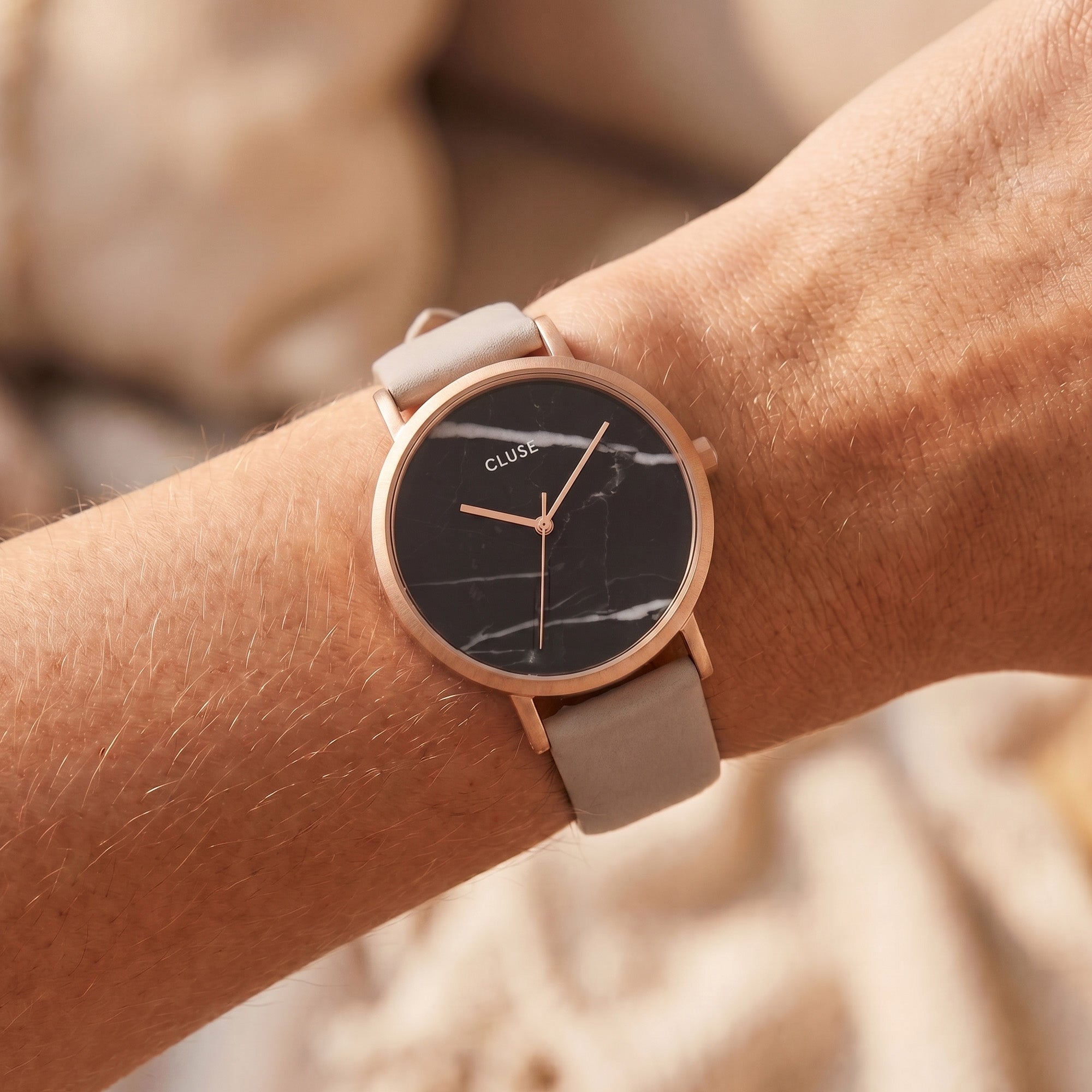 Woman wearing Cluse La Roche rose gold black marble/grey watch on her wrist.