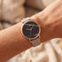 Woman wearing Cluse La Roche rose gold black marble/grey watch on her wrist.