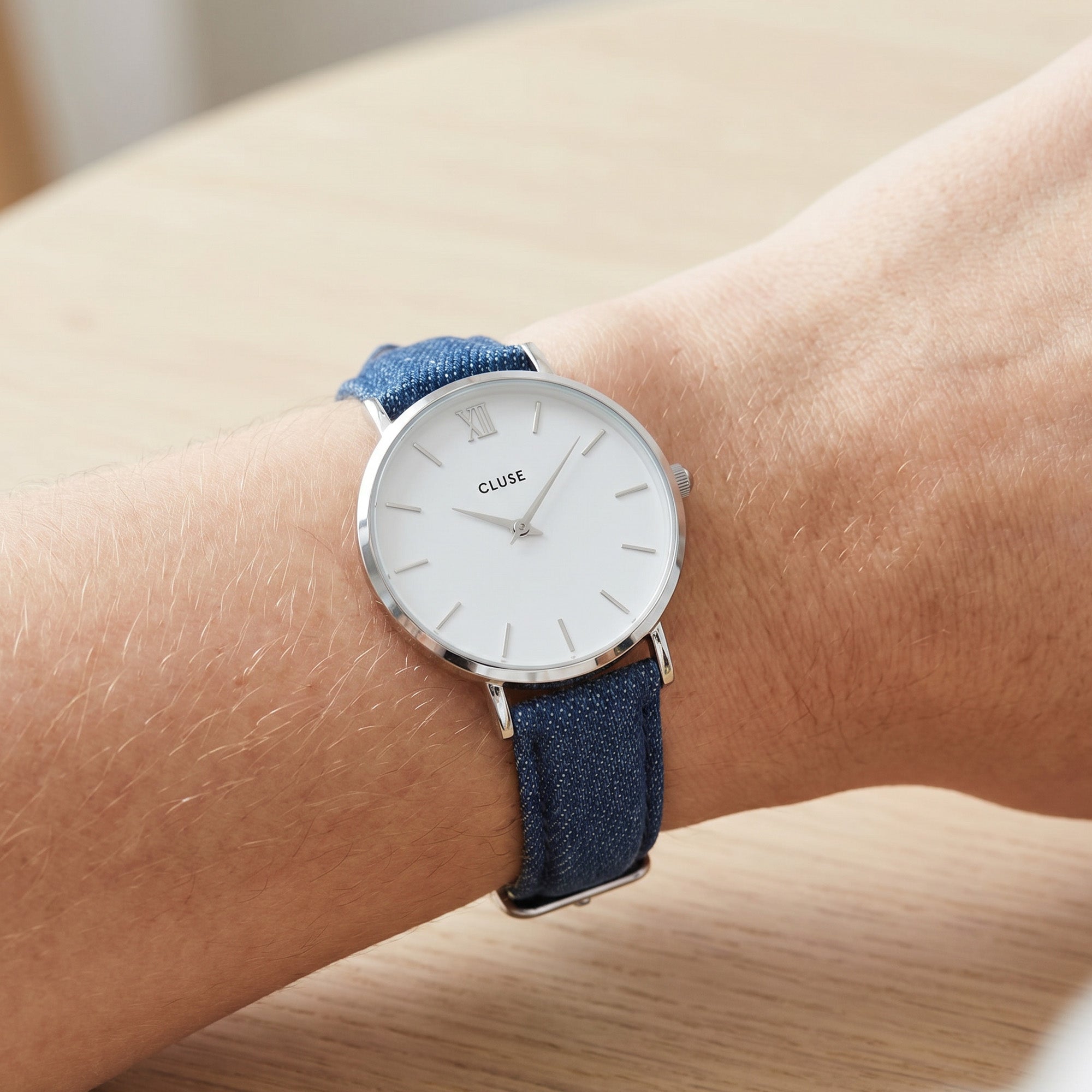 Close-up of woman's wrist wearing Cluse Minuit silver/white denim watch.