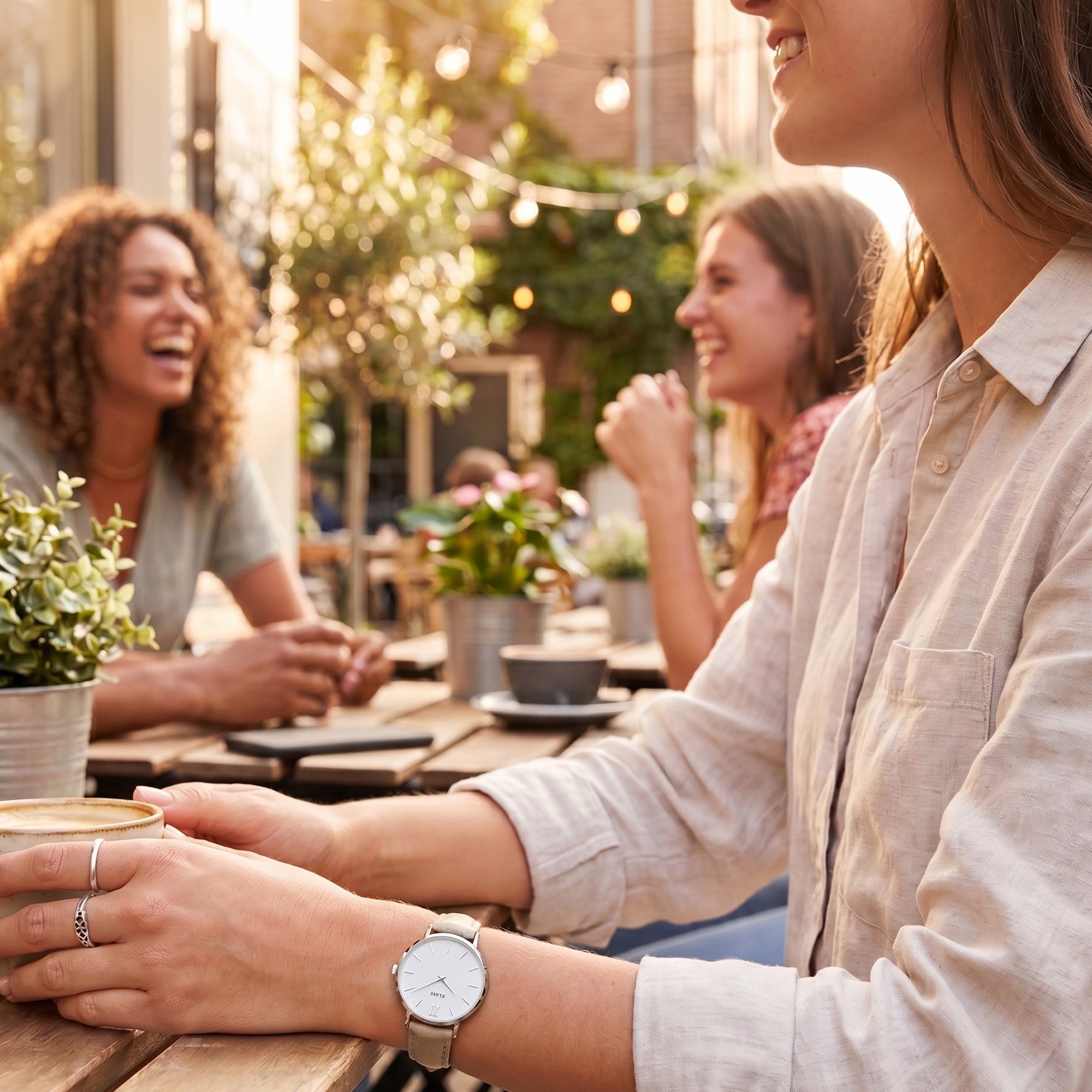 Woman wearing Cluse Minuit silver/white dow brown watch at an outdoor cafe.