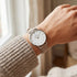 Woman wearing Cluse Minuit silver/white doe brown watch on her wrist.
