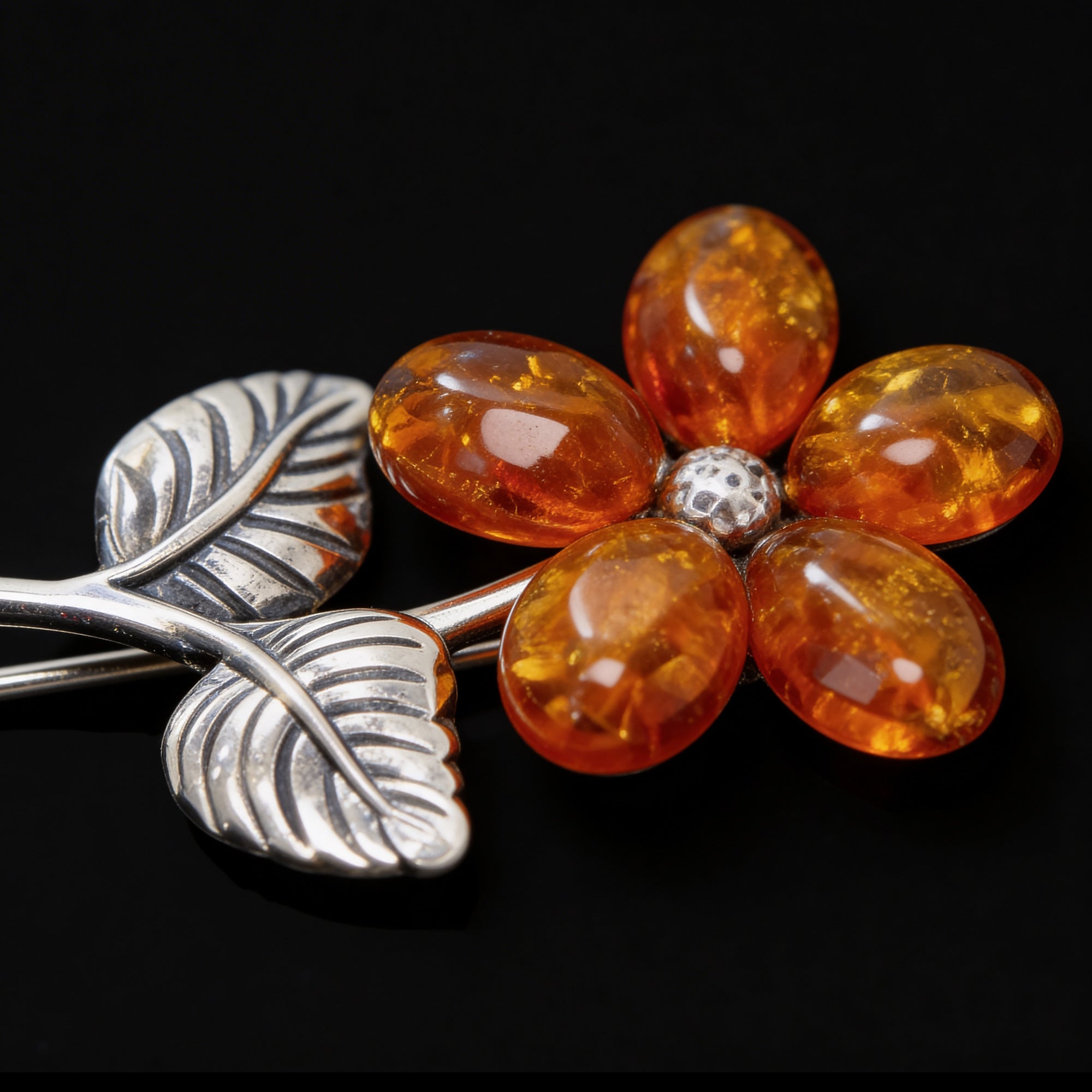 Close-up of a cognac Baltic amber sterling silver flower brooch showing leaf detailing and amber.