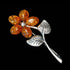 A cognac Baltic amber sterling silver flower brooch tilted to the left.