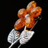 A cognac Baltic amber sterling silver flower brooch in side close-up.