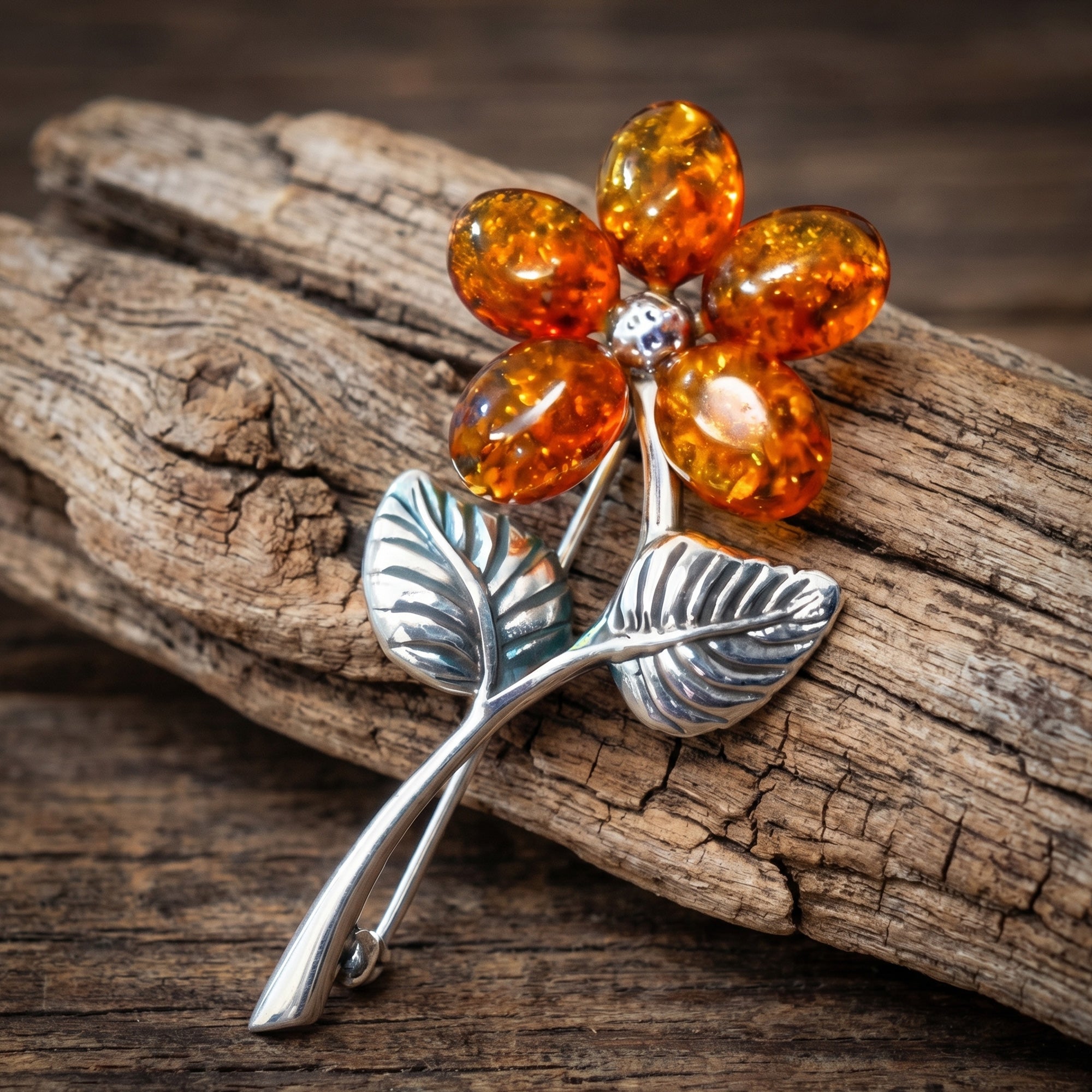 A cognac Baltic amber sterling silver flower brooch wresting against a piece of desiccated wood.