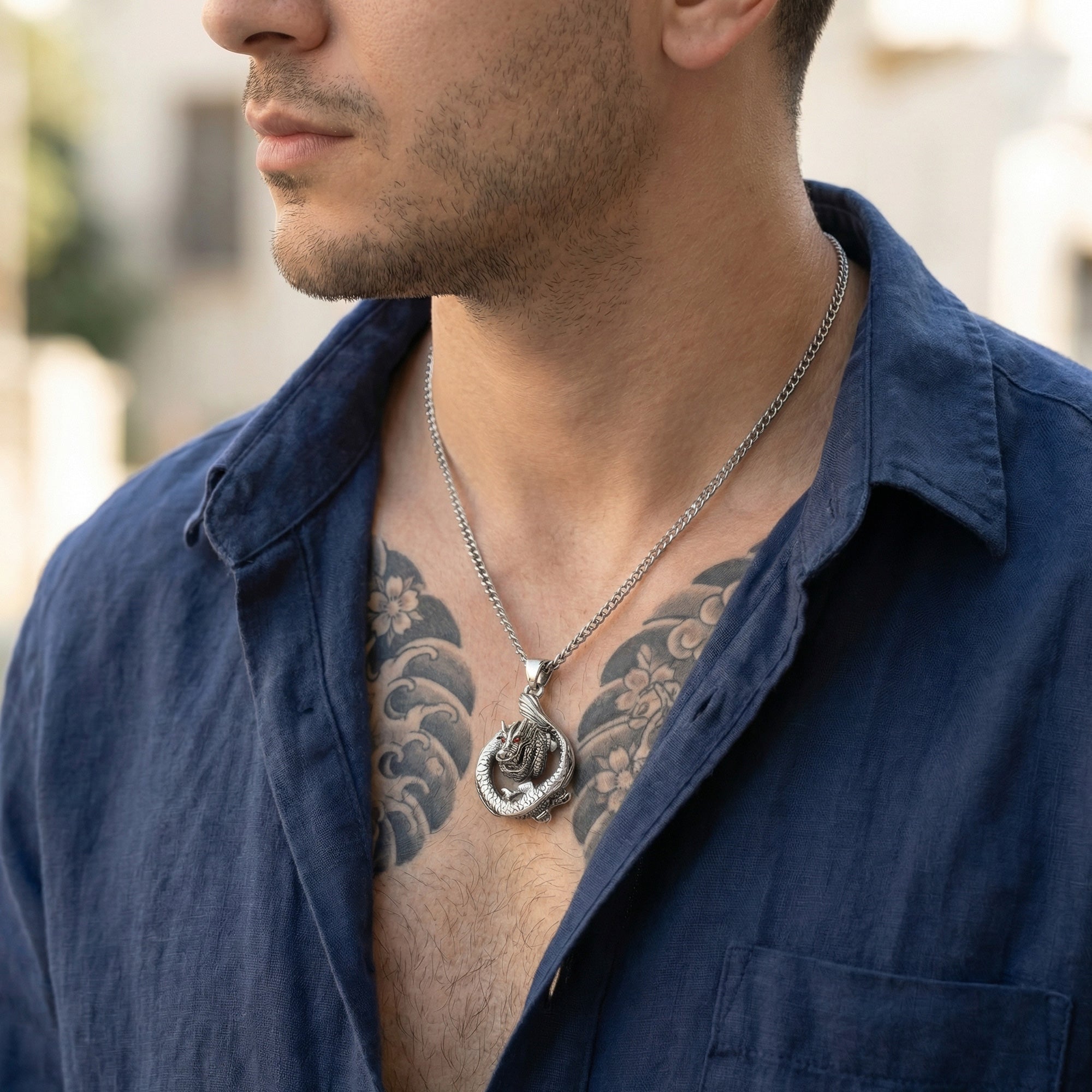 Man with a tattooed chest wearing a coiled dragon stainless steel necklace.