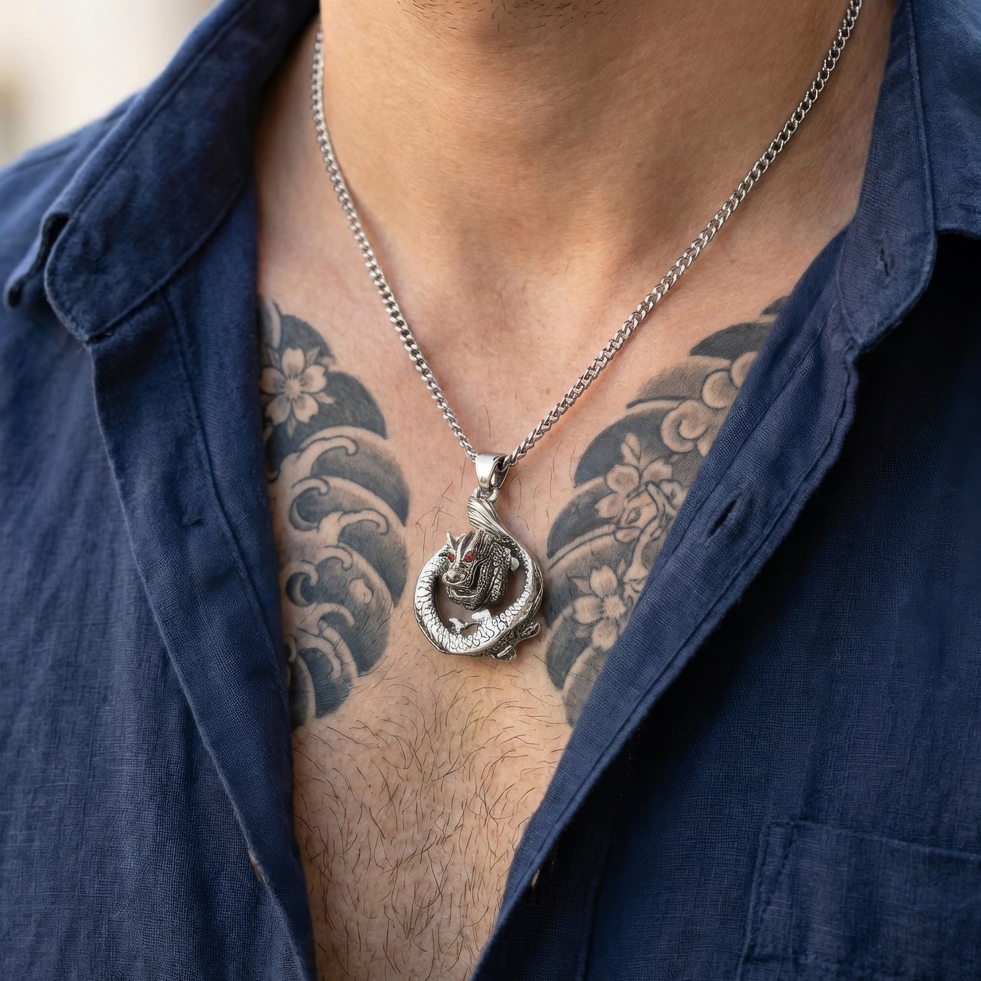 Close-up of a man with a tattooed chest wearing a coiled dragon stainless steel necklace.