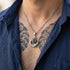 Close-up of a man with a tattooed chest wearing a coiled dragon stainless steel necklace.