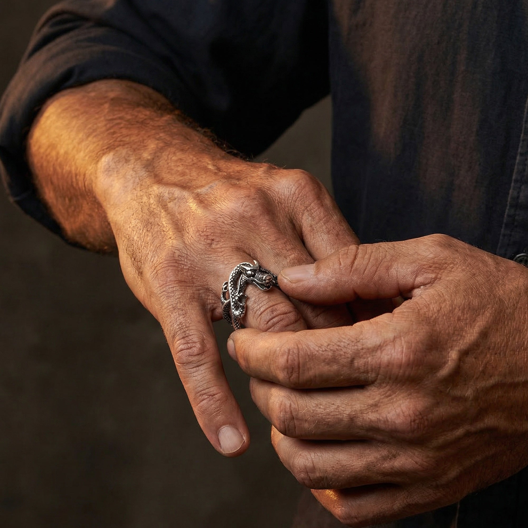 Man placing a coiled dragon stainless steel ring onto his hand.