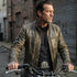 Biker man with his hands on a motorcycle's handlebars wearing a black leather belt with a Celtic cross shield, dagger and skull belt buckle.
