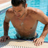 Man about to jump out of swimming pool wearing faith cross & wing stainless steel necklace.