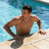 Man standing in swimming pool, about to emerge, wearing faith cross & wing stainless steel necklace.