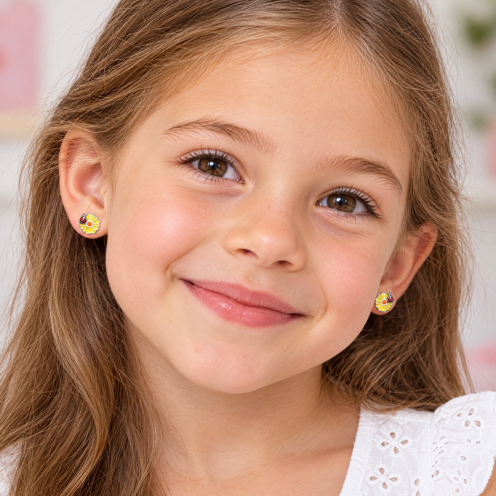 A young girl wearing daisy ladybird enamel children’s sterling silver earrings.
