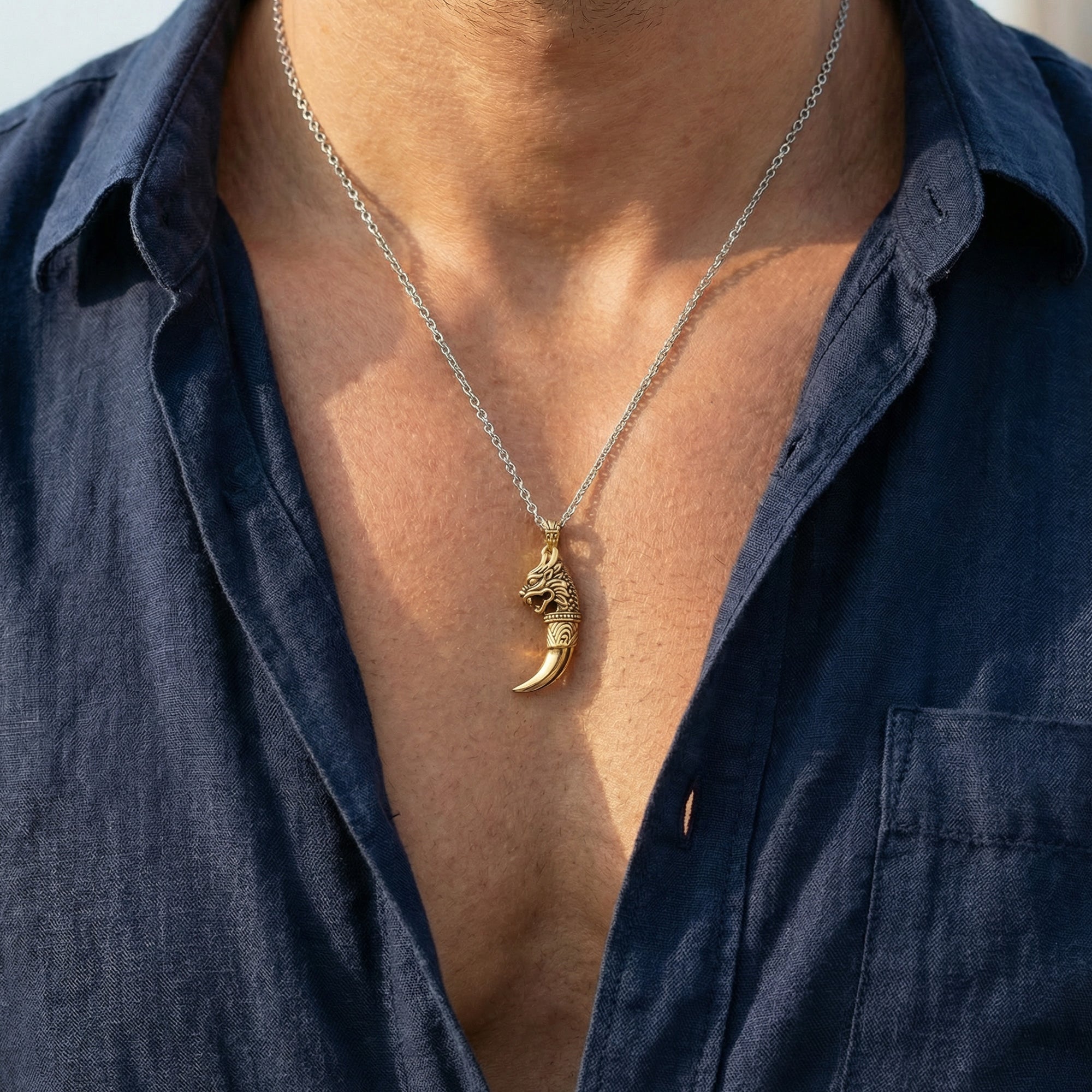 Close up of a man in an open-neck shirt wearing a gold dragon tooth men's necklace.