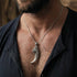 Close-up of a man in an open-neck shirt wearing a sterling silver dragon tooth pendant. 