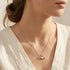 Close up of a woman wearing an Engelsrufer Faith Love & Hope Sterling Silver Necklace. 