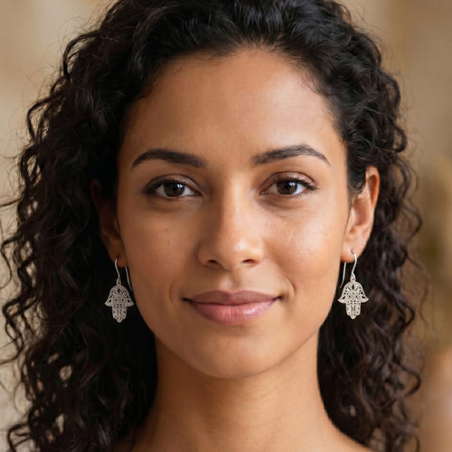 Woman wearing Engelsrufer Fatima’s Hand silver hook earrings.