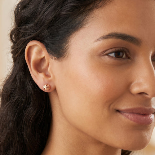 Woman wearing Engelsrufer filigree cage ball rose gold stud earrings.