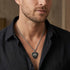 Close-up of a man in an open-neck shirt wearing fleur-de-lis cross medallion necklace.