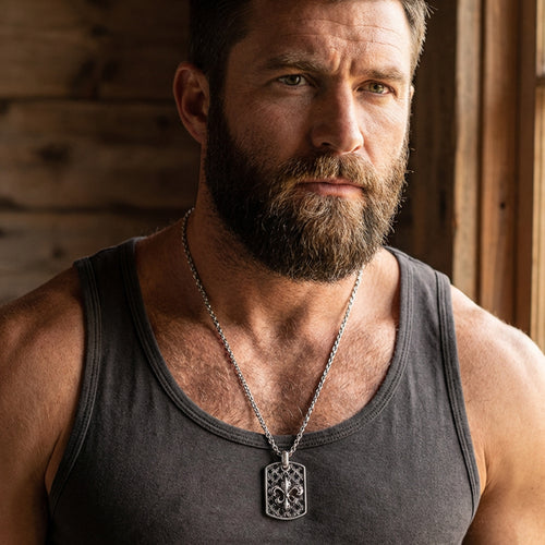 Close-up of man in a singlet wearing a fleur-de-lis dog tag necklace.