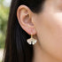 Woman wearing Engelsrufer gold ginkgo leaf hook earrings.