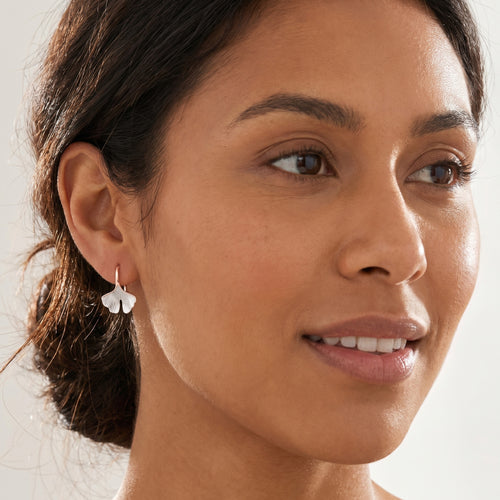 Woman wearing Engelsrufer rose gold ginkgo leaf hook earrings.
