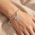 Engelsrufer ginkgo silver charm attached to a bracelet being worn on a woman's wrist.