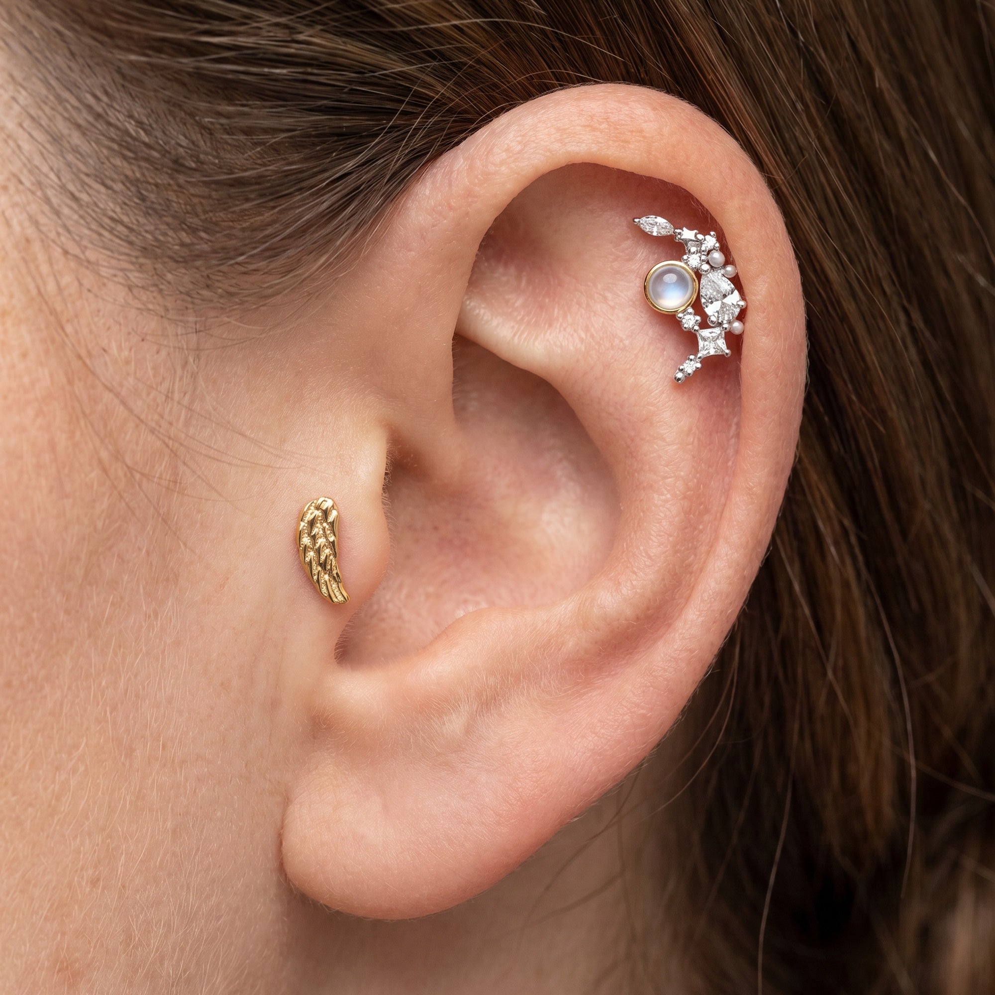 Woman wearing Engelsrufer moon & gold angel wing mismatch stud earrings.