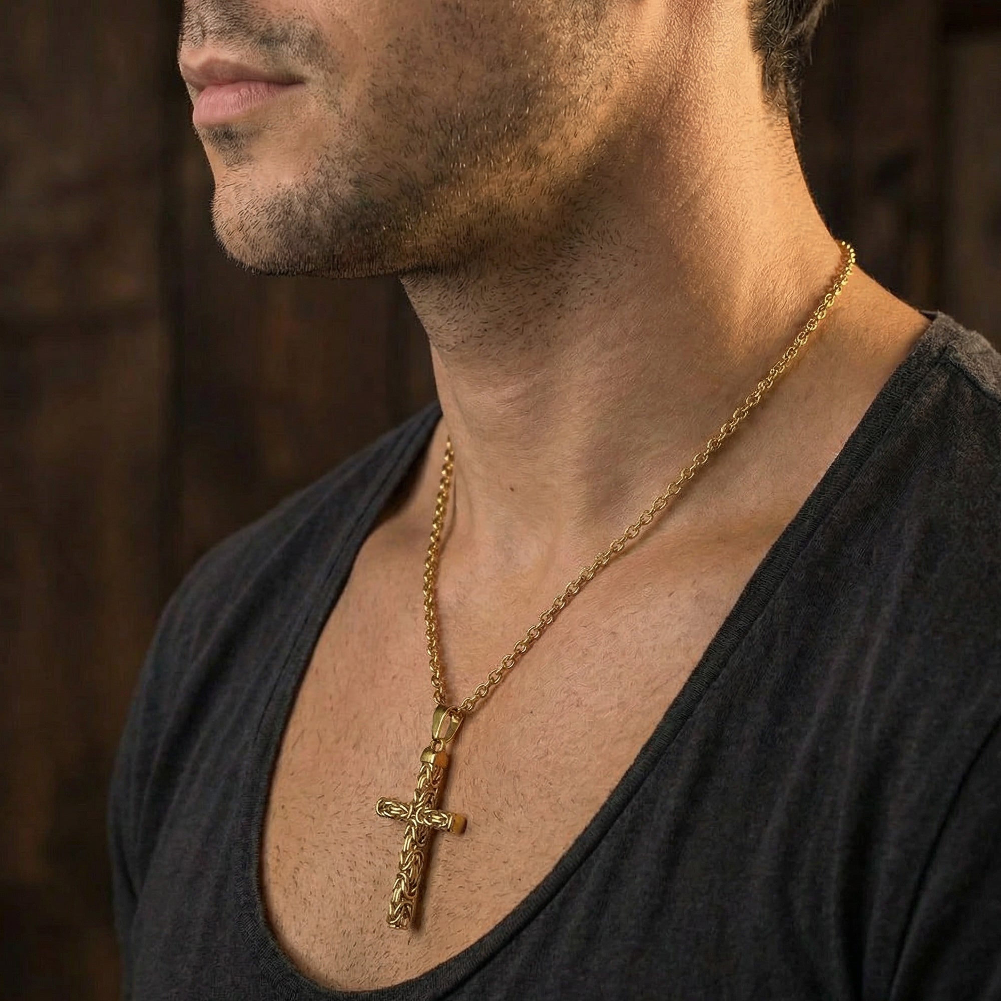 Close-up side profile of man wearing Byzantine rope knot cross gold stainless steel necklace.