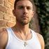 Man in a white singlet wearing faith cross & wing steel gold necklace.