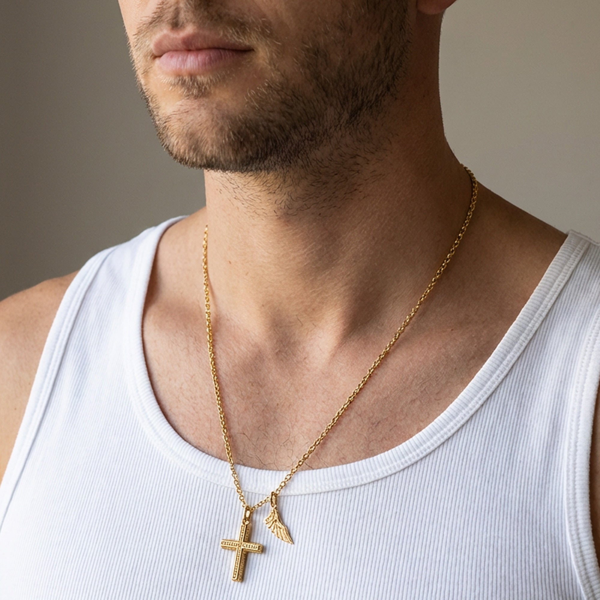 Close-up of a man wearing Save Brave faith cross & wing steel gold necklace.