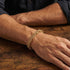 Man wearing Save Brave byzantine chain men's gold steel bracelet on his wrist.