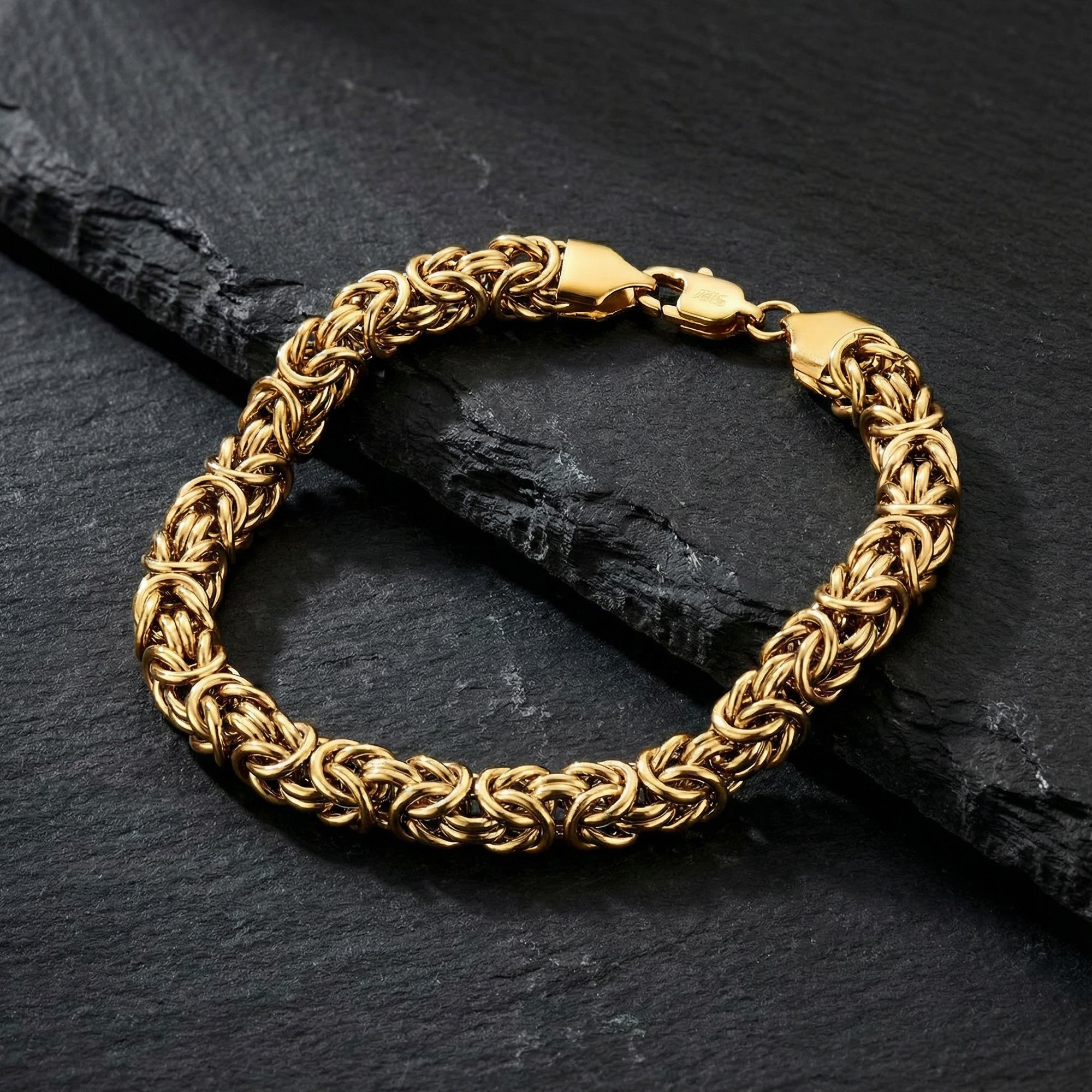 Byzantine chain men's gold steel bracelet on black slate.