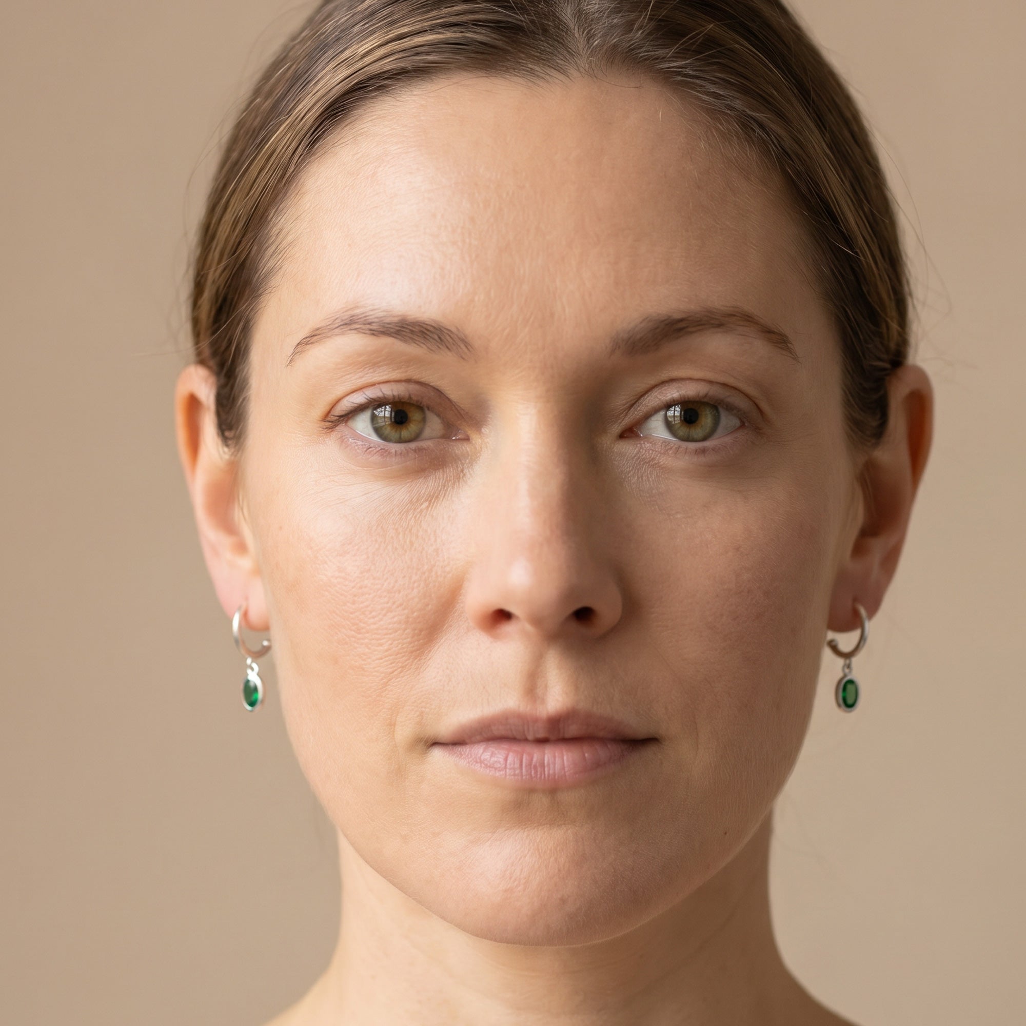 Woman wearing a pair of Engelsrufer green CZ hoop dangle earrings.