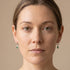 Woman wearing a pair of Engelsrufer green CZ hoop dangle earrings.
