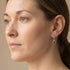 Woman wearing Engelsrufer green CZ hoop dangle earrings.