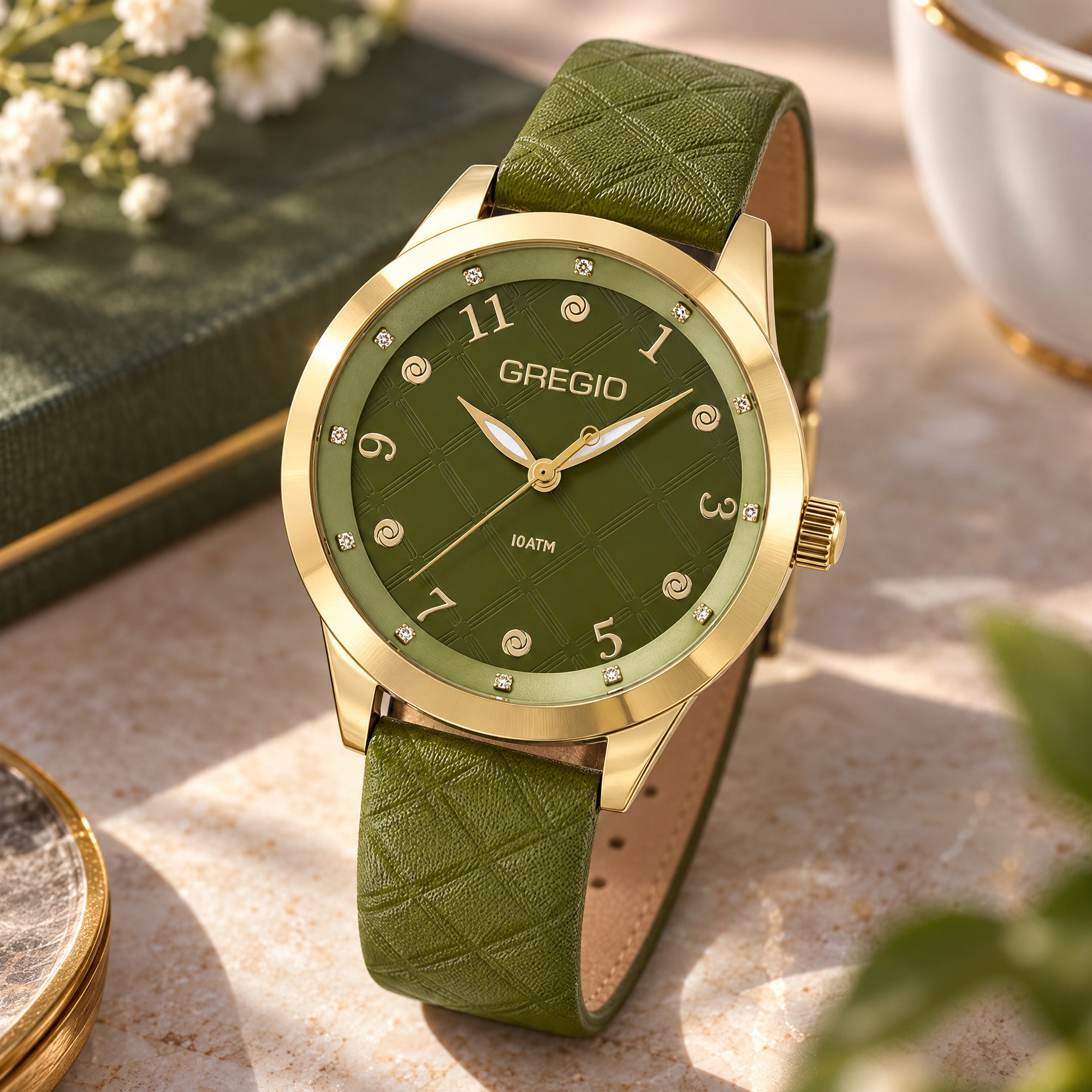 Gregio Porto Grace olive watch on a table with a leather bound book.