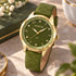 Gregio Porto Grace olive watch on a table with a leather bound book.
