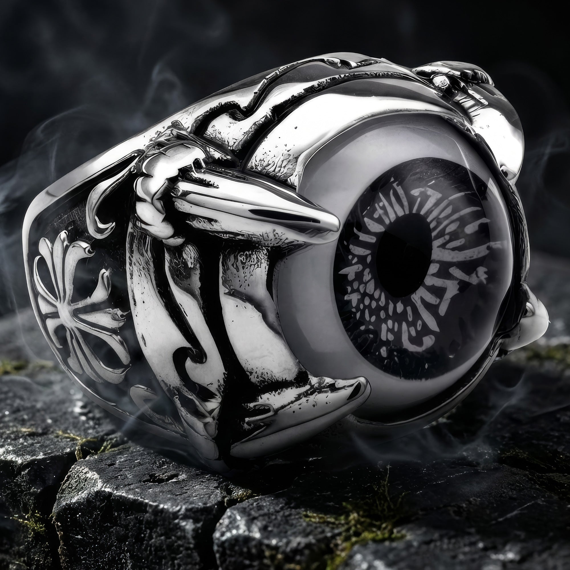 Grey eyeball dragon claw stainless steel men's ring on black stones with moss and rising smoke.