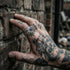 Man with tattooed hand touching a bring wall wearing grey eyeball dragon claw stainless steel men's ring.