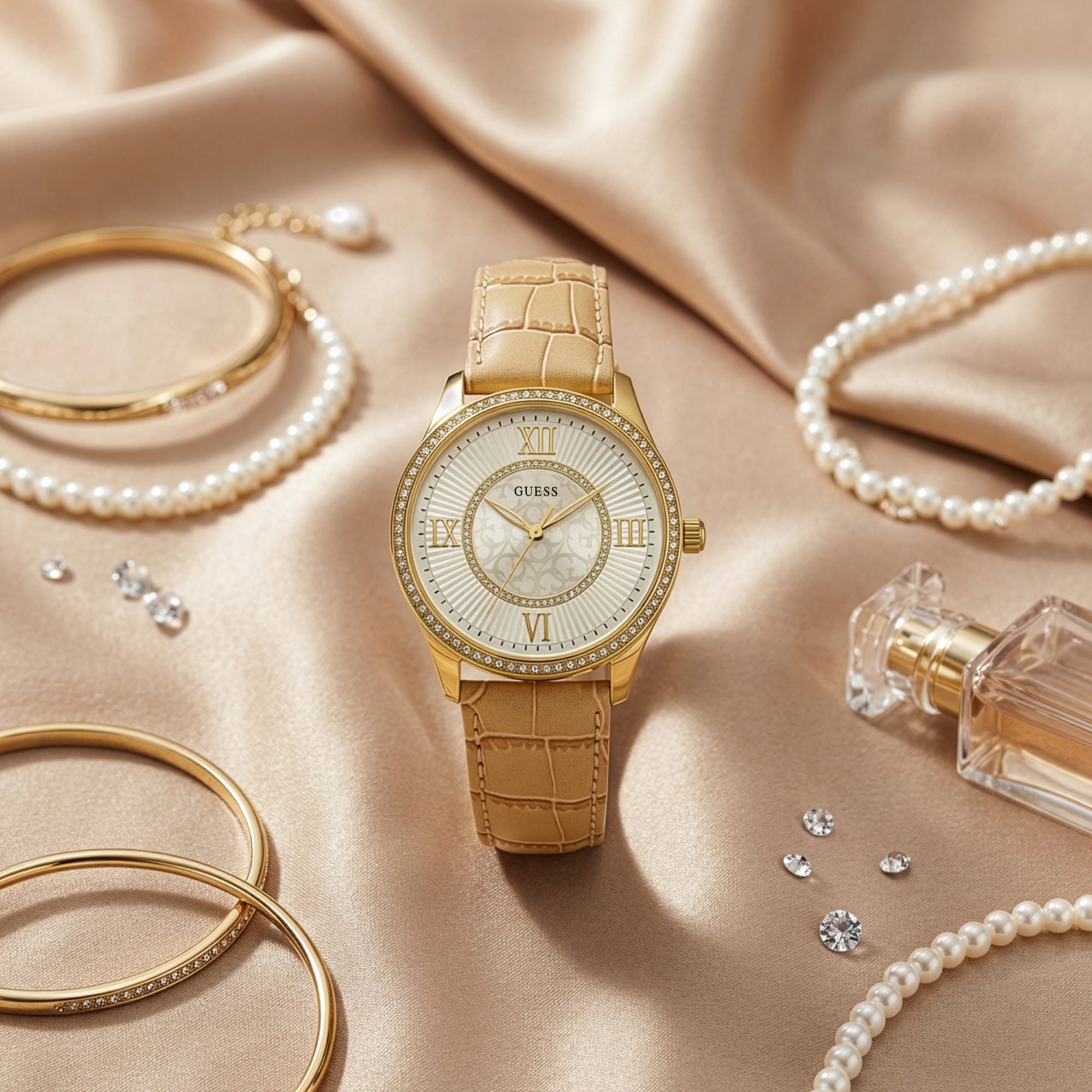 Guess Broadway gold ladies dress watch on beige fabric surrounded by jewellery.