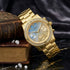Guess Confetti gold ladies sport watch on a marble table with books and gemstones.