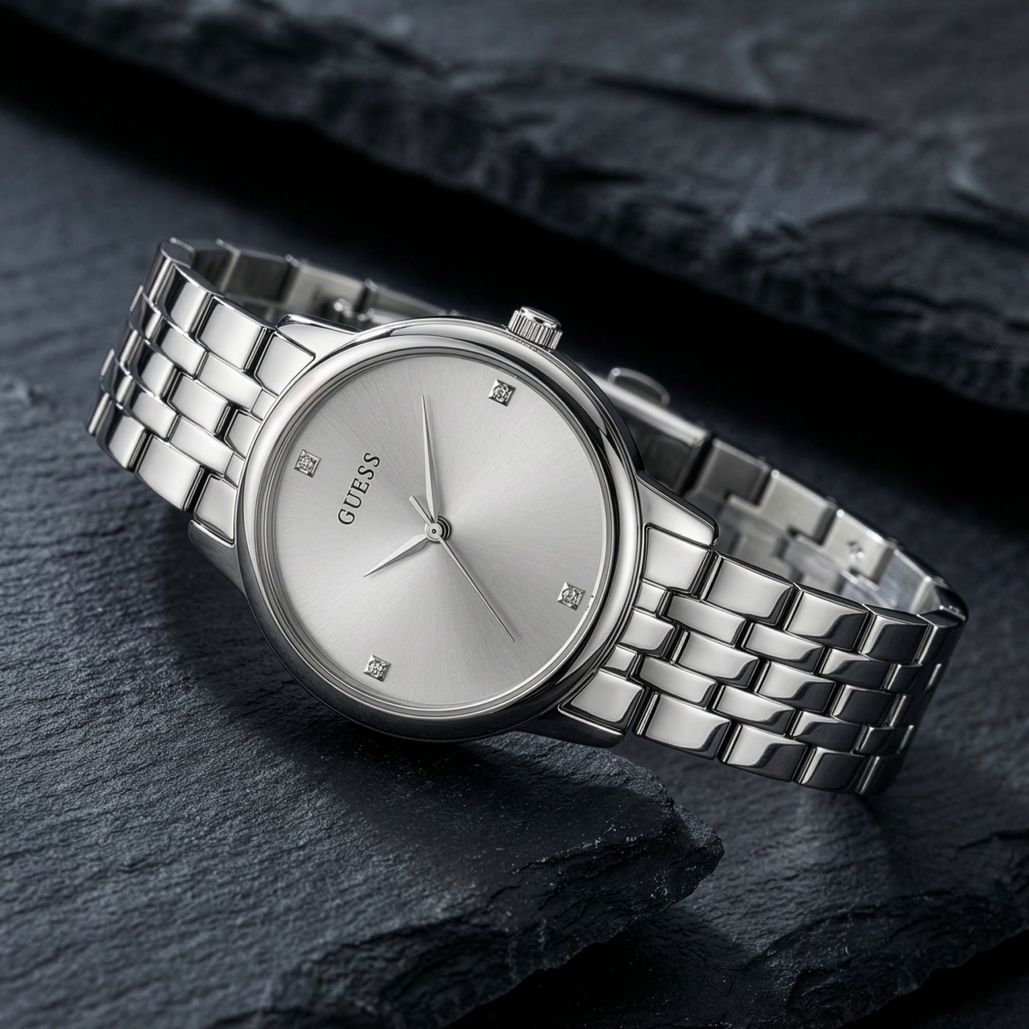 Guess Lady Wafer silver dress watch on a black rock background.