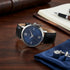 Guess VP blue dial men's dress watch on a wooden table with cufflinks.