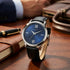 Guess VP blue dial men's dress watch on a wooden desk.