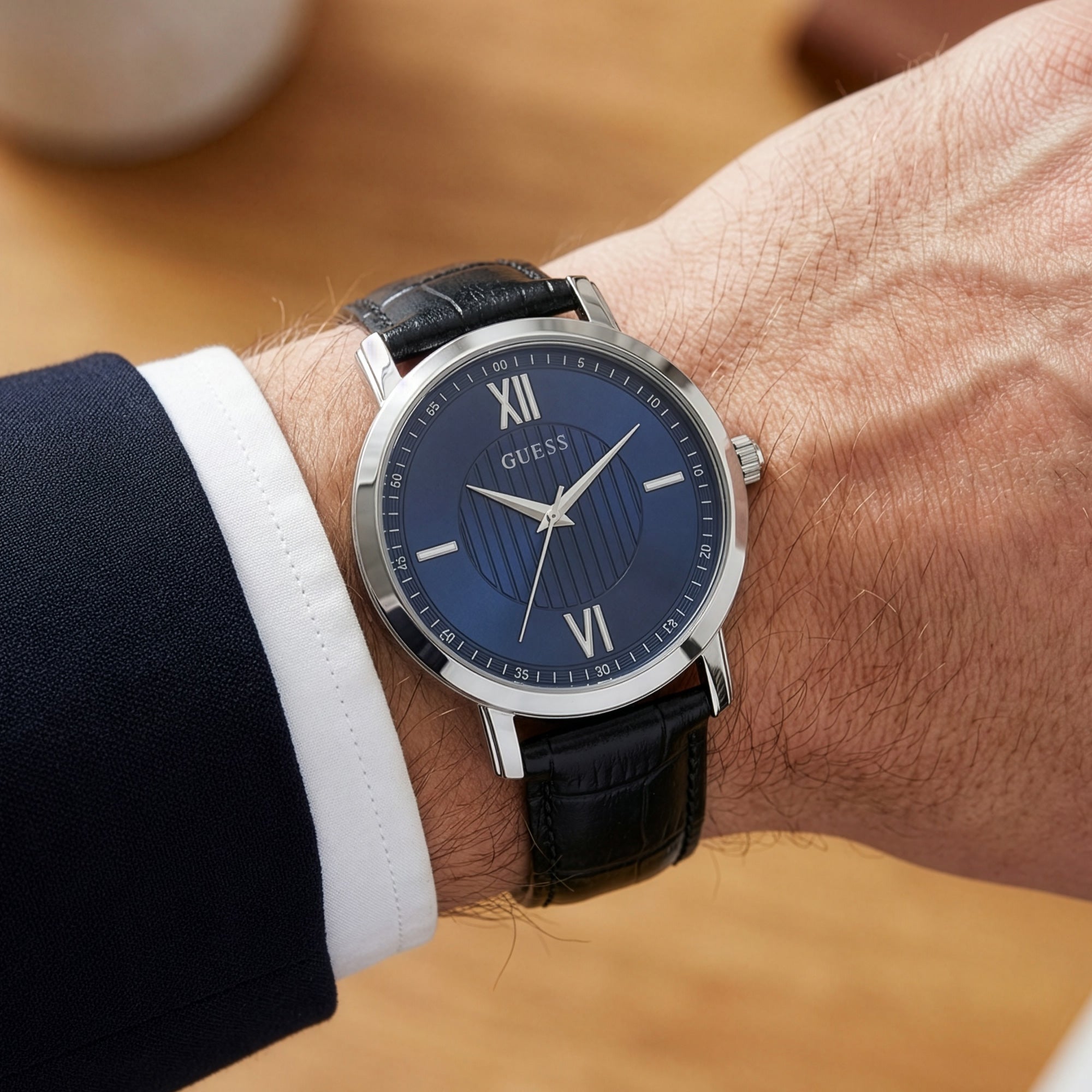Man wearing Guess VP blue dial dress watch on his wrist.