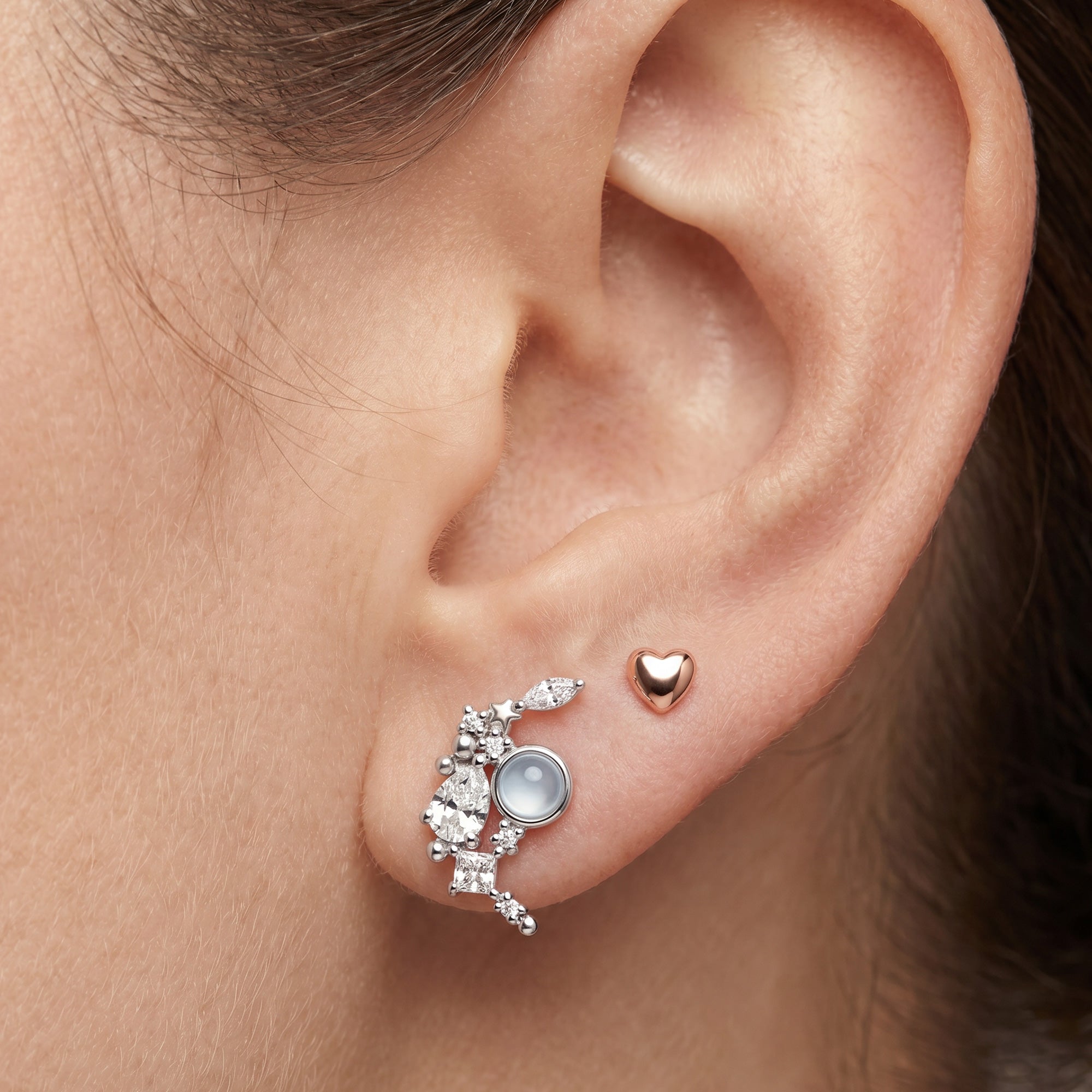 Close-up of woman wearing Engelsrufer heart & moon mismatch sterling silver earrings.