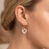 Close-up of a woman wearing sterling silver rose gold white ceramic heart earrings.